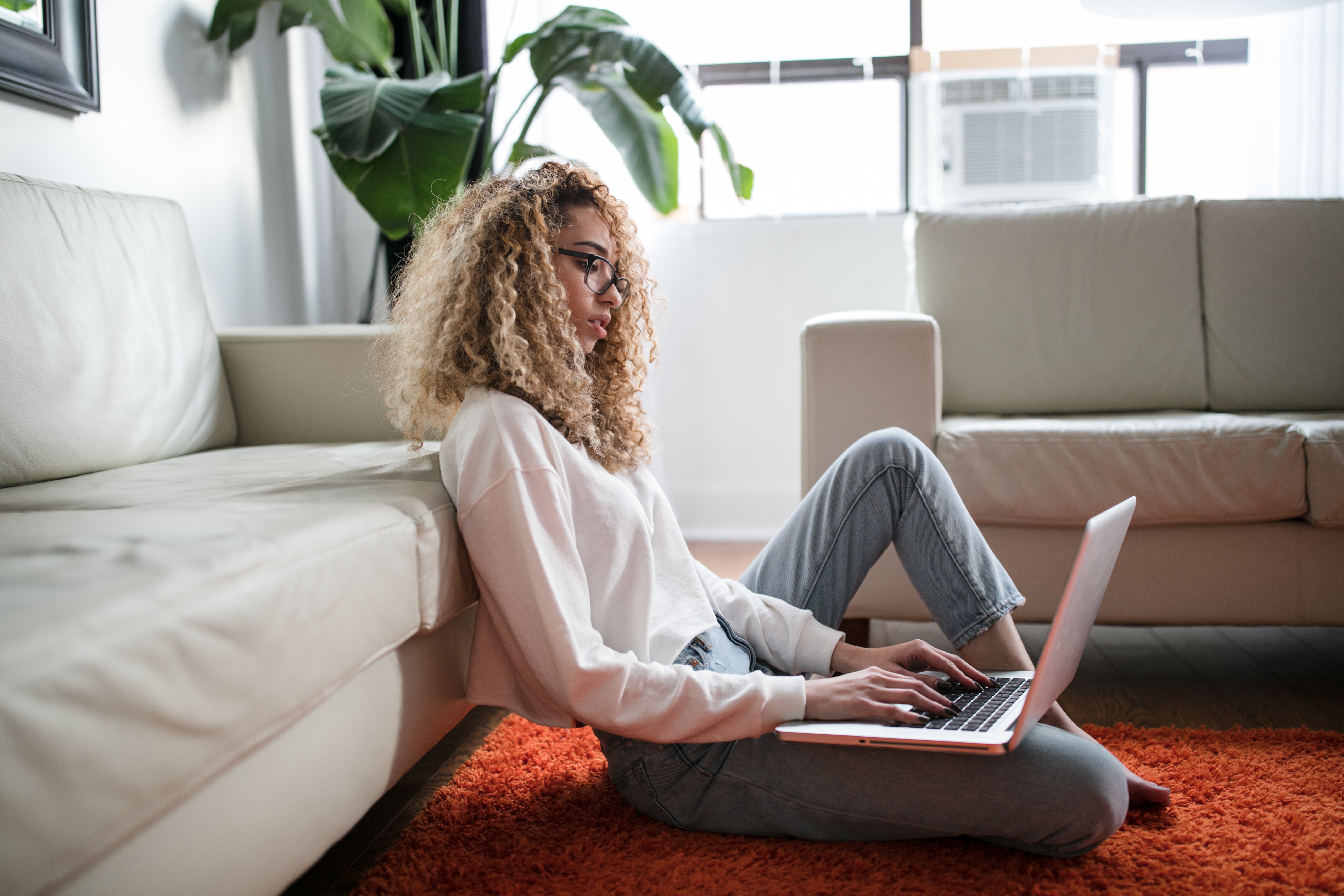 Photo of a woman sitting on the floor using her laptop.