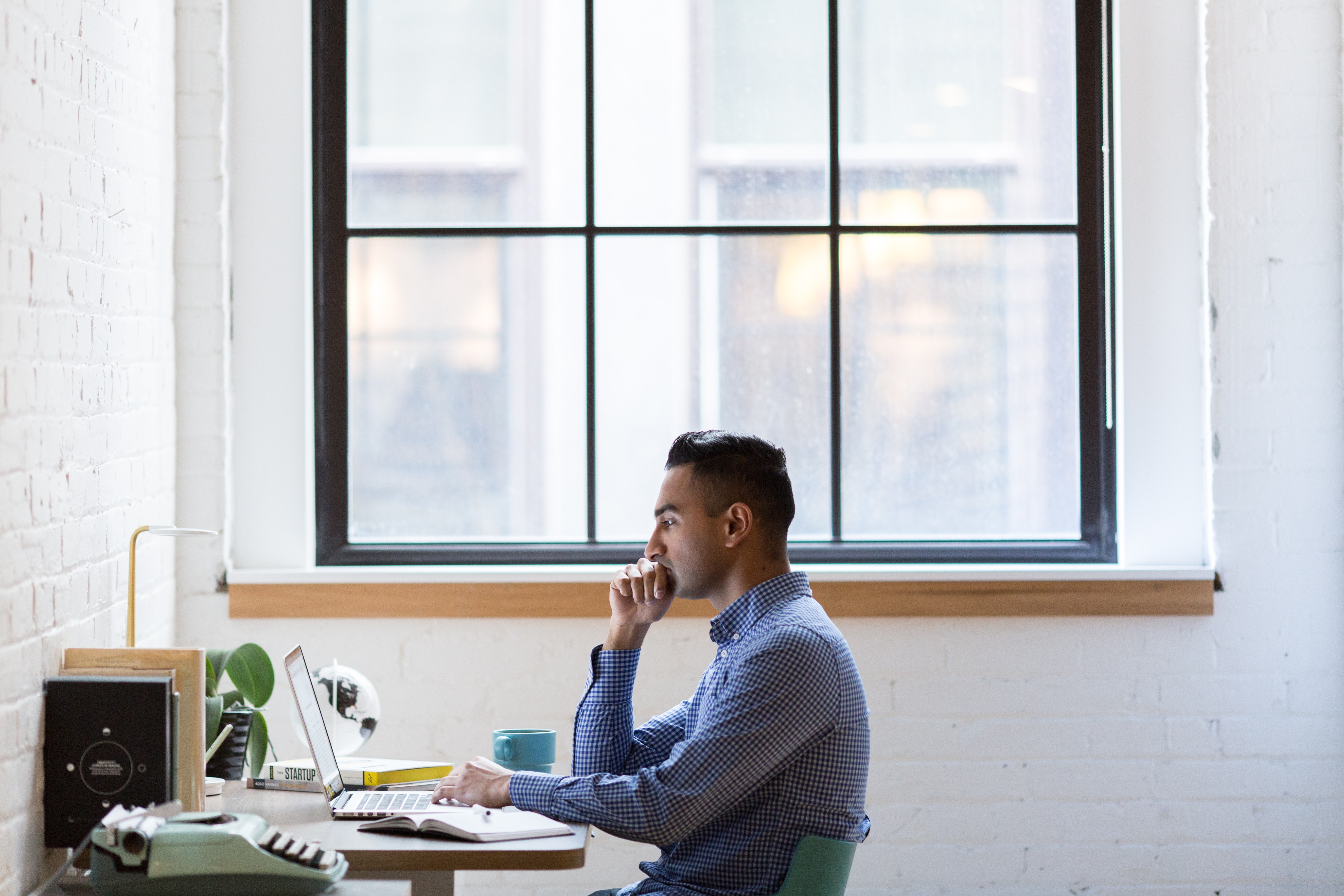 Photo of a man doing health and medical writing front of a laptop in a home office.