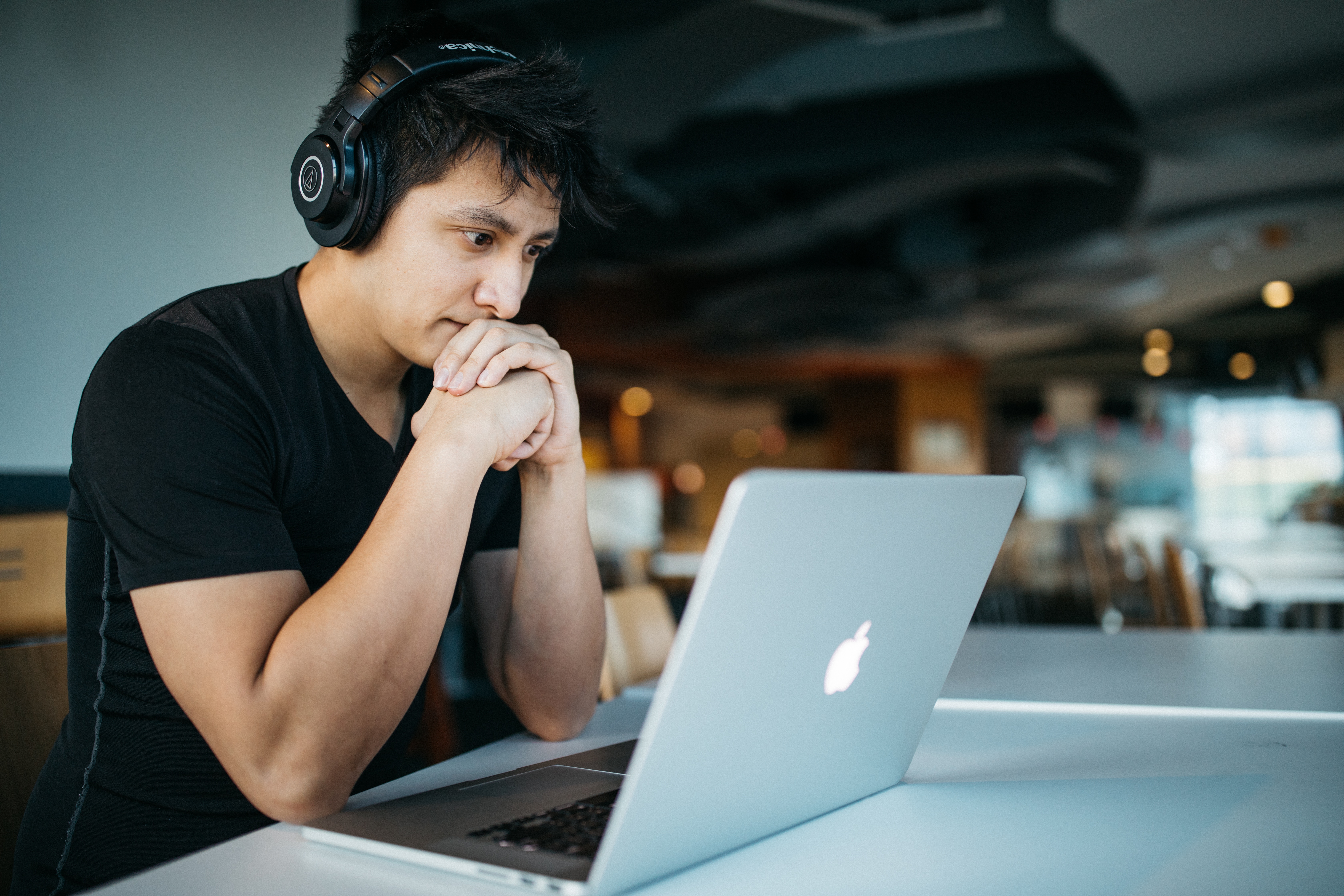 Photo of a man wearing headphones and using a laptop.