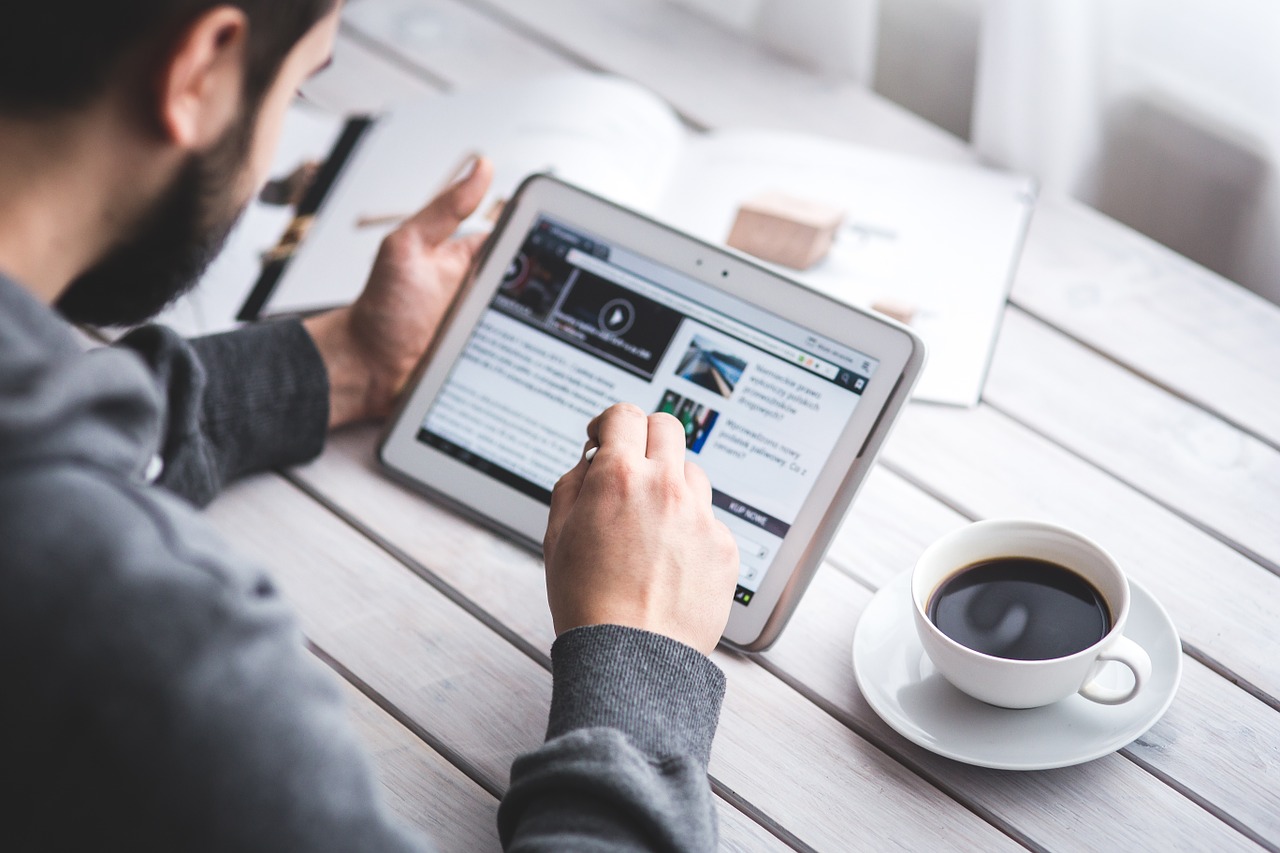 Photo of a man browsing a blog on a tablet.