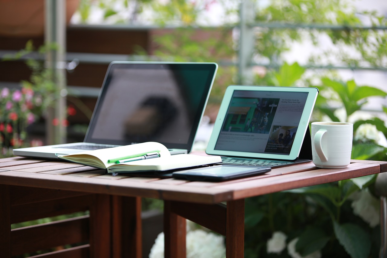 Photo of a laptop, tablet, and book on a desk.
