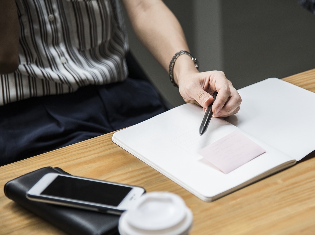 Photo of a man sitting at a desk with a notepad during a meeting.