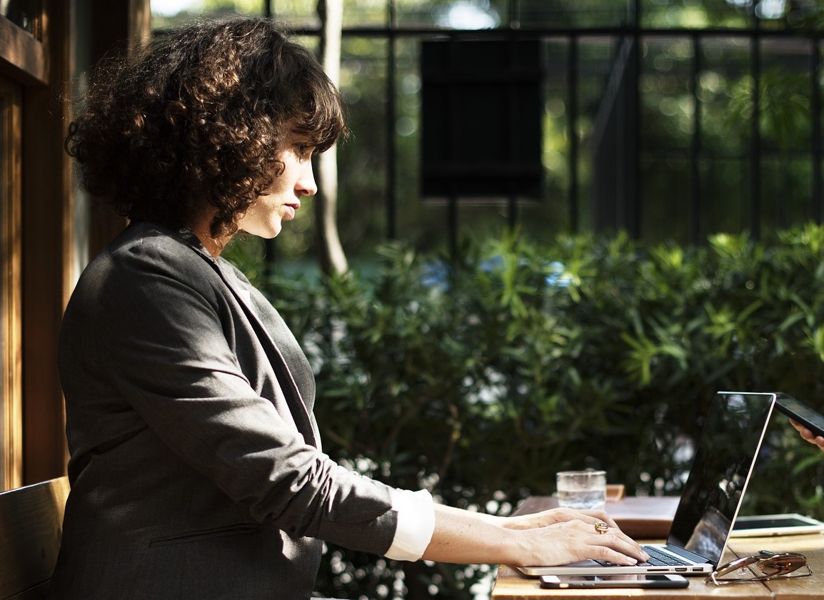 Photo of a woman in a suit working outside on a laptop.