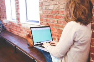 Photo of a woman relaxing while using her laptop.