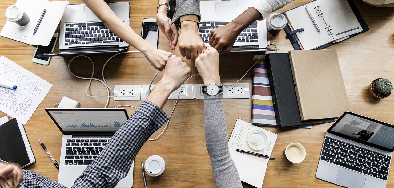 Photo of a several people fist-bumping at a networking event.