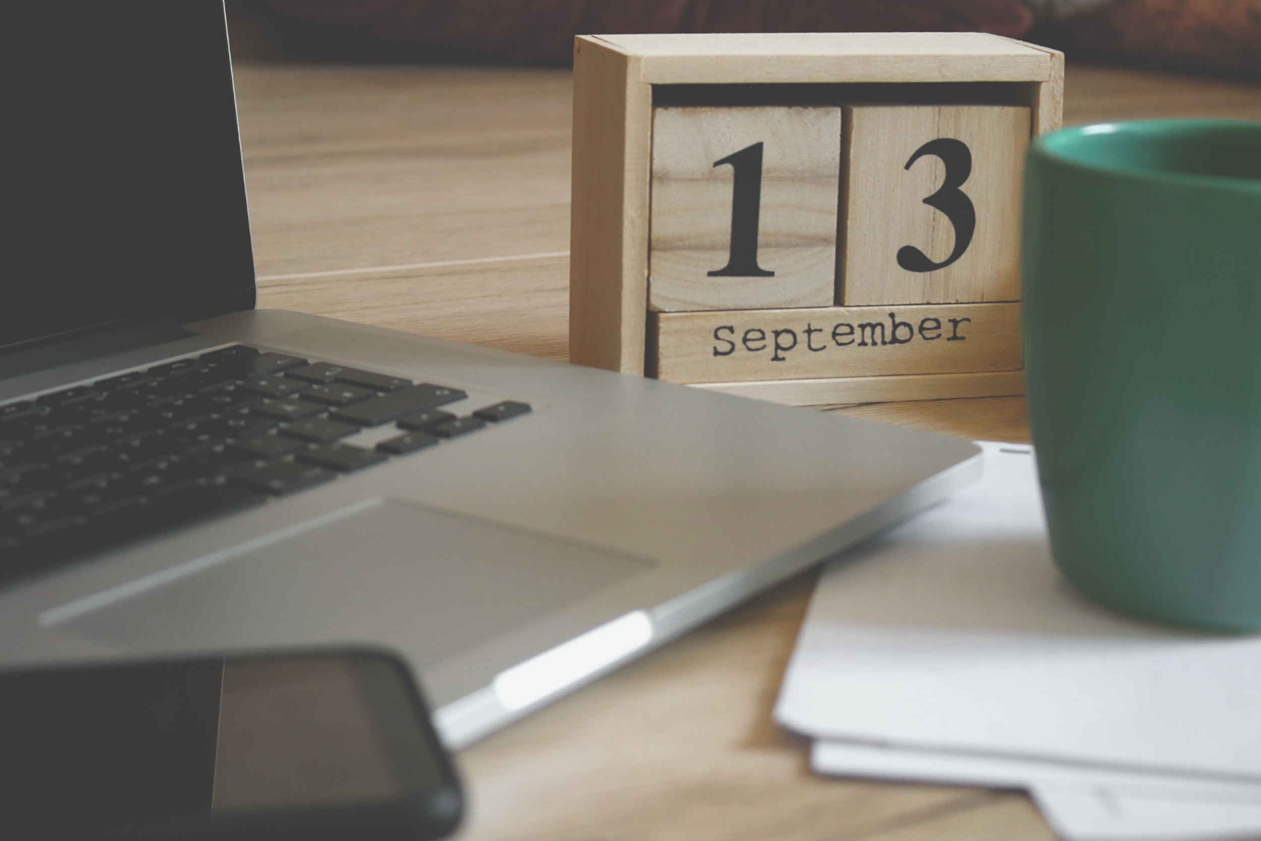 Photo of a laptop next to a wooden calendar.