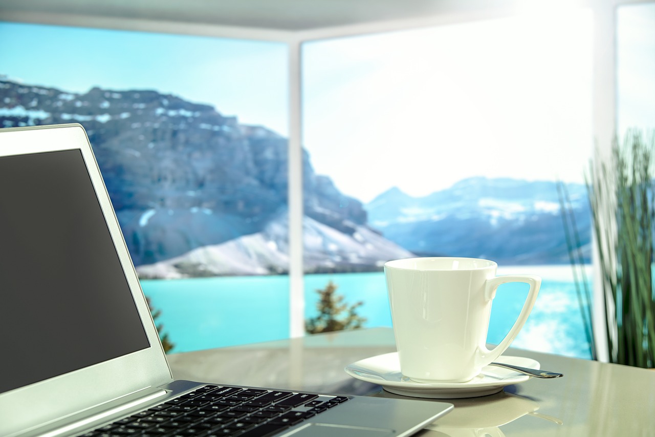 Freelance writer's laptop on a desk, overlooking a beautiful lake.